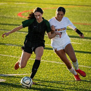 Soccer player chases ball while trying to block opponent